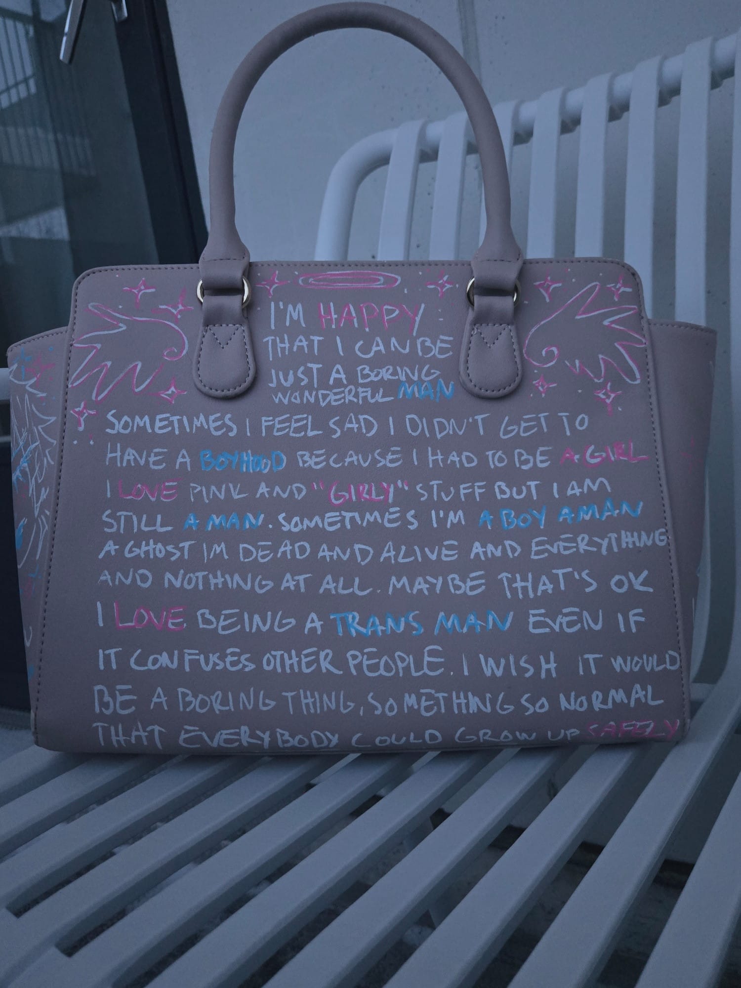 bag covered in blue, pink, and white writing on the joy of being trans even if it confuses others